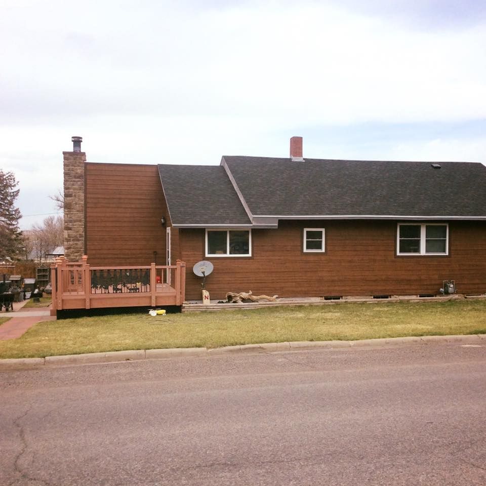 Brown house with a deck, chimney, and satellite dish.