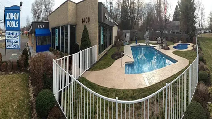 A large swimming pool is surrounded by a white fence.