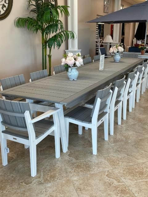 A long table with chairs and a vase of flowers on it
