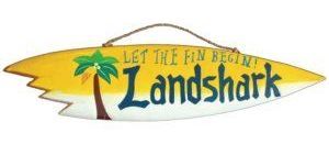 A surfboard with the words let the fun begin landshark on it