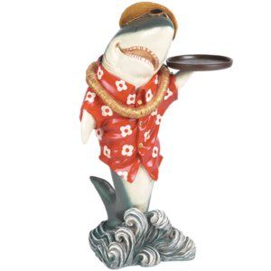 A statue of a shark wearing a red shirt and hat holding a tray.