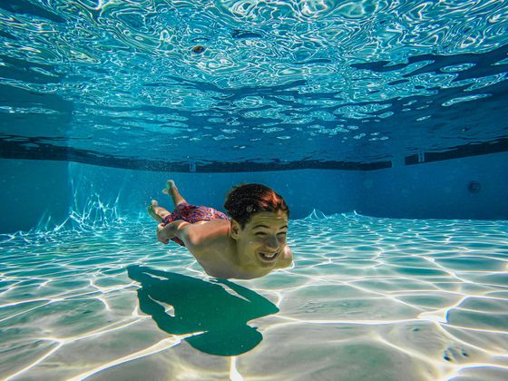 A young boy is swimming underwater in a swimming pool.