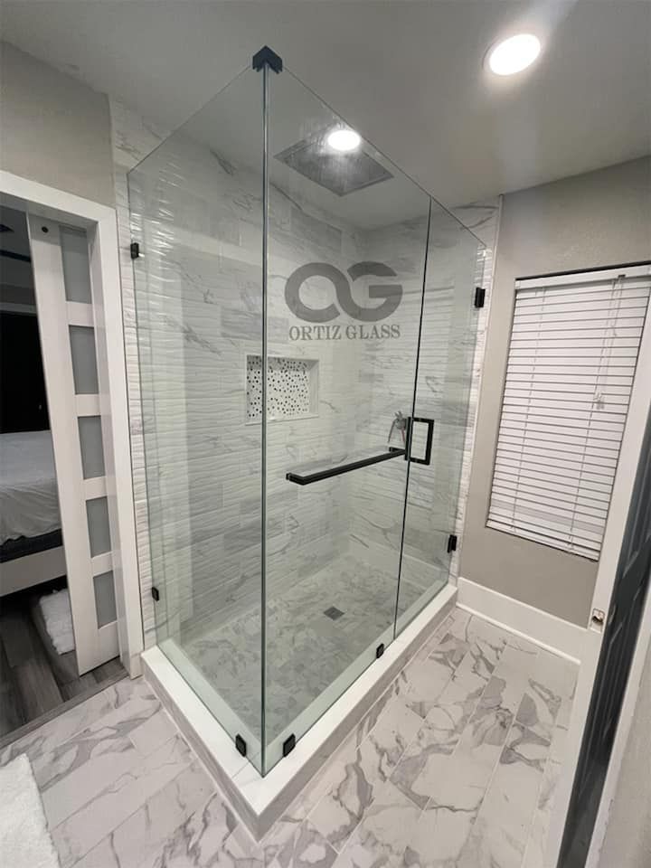 A bathroom with a glass shower door and a black handle.