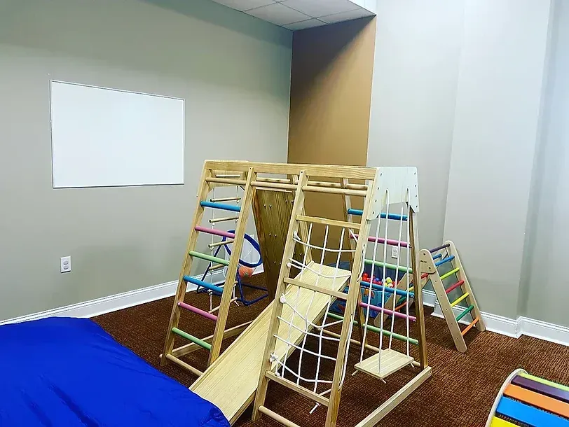 A child is playing in a room with a wooden playground.