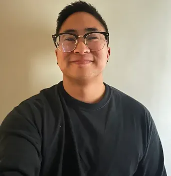 A man wearing glasses and a black shirt smiles for the camera