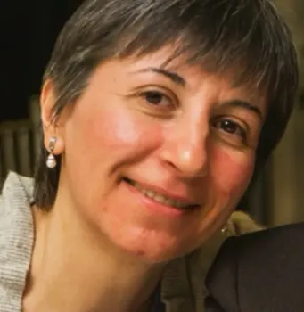 A woman wearing pearl earrings smiles for the camera