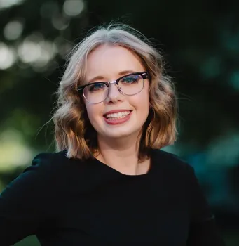 A woman wearing glasses and a black shirt is smiling for the camera.