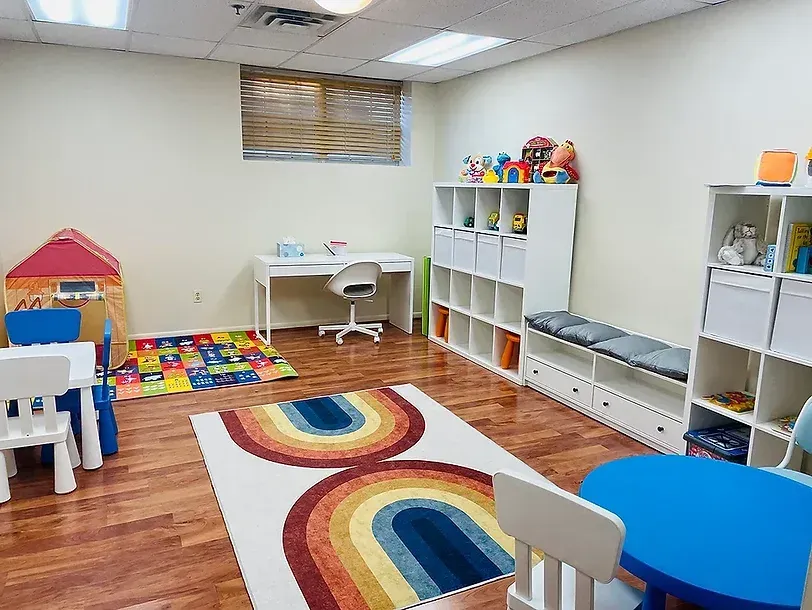 A child 's room with tables , chairs , a rug and a desk.