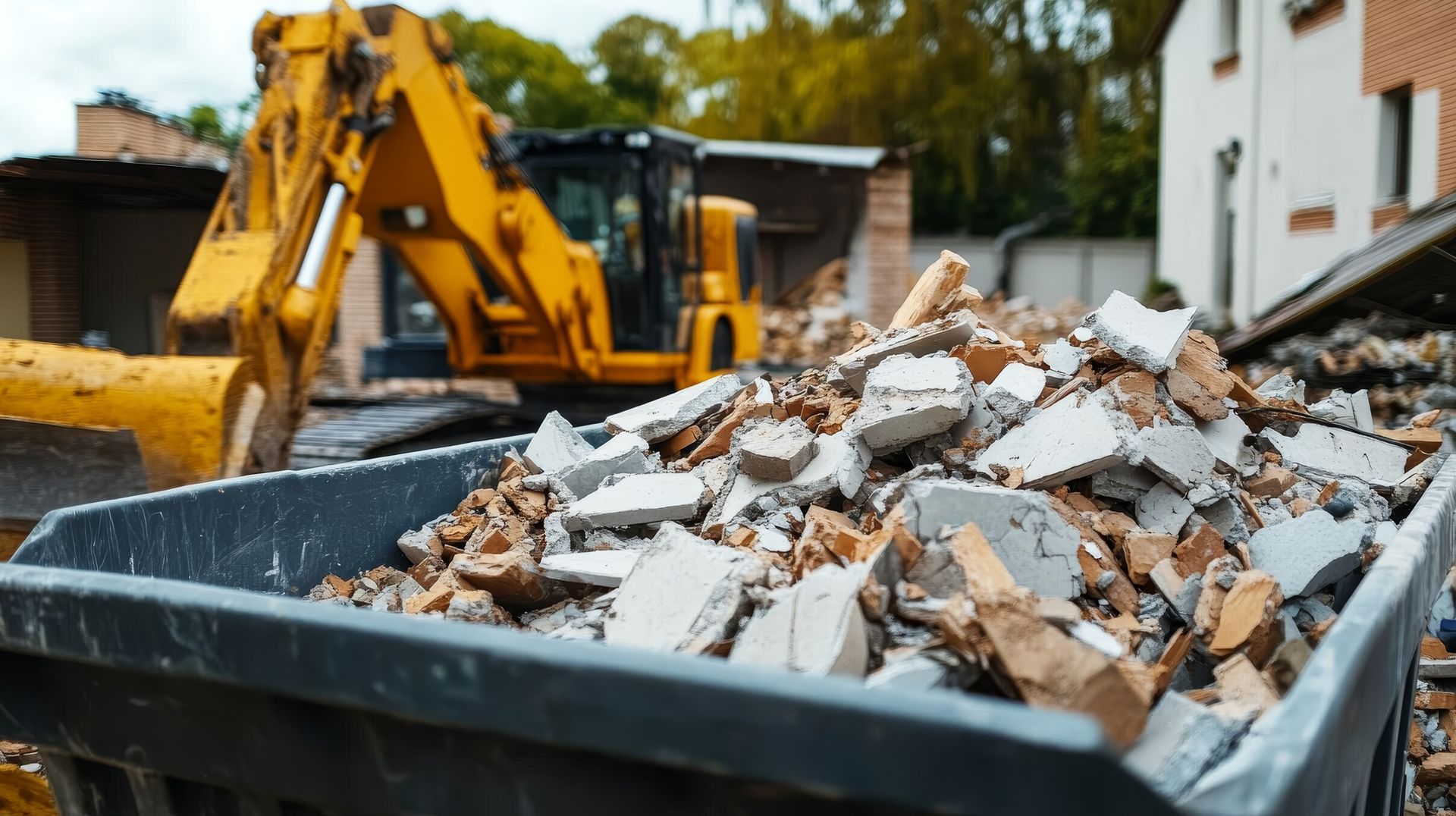 Dumpster filled with construction debris, with an excavator in the background at a demolition site