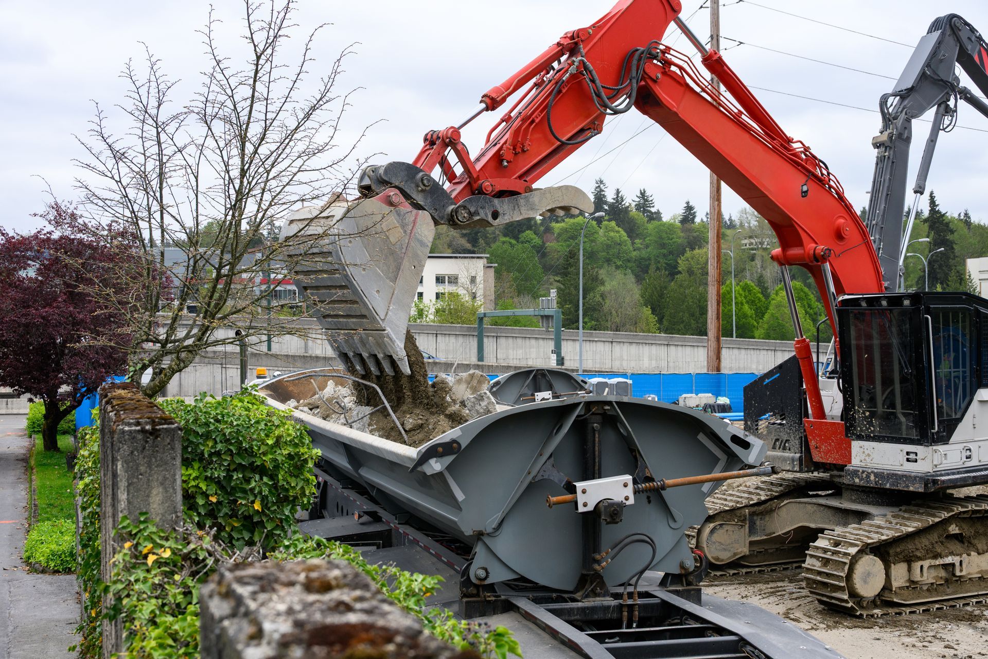 Red excavator dumping rubble into a crusher on a construction site