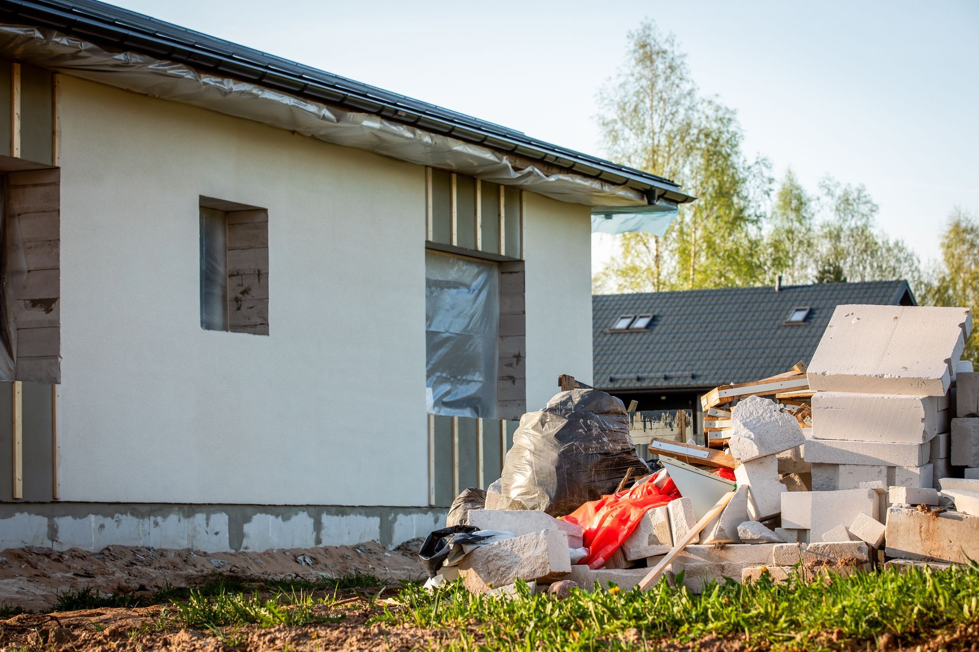 Demolished wall beside a house, with rubble and debris on the lawn.