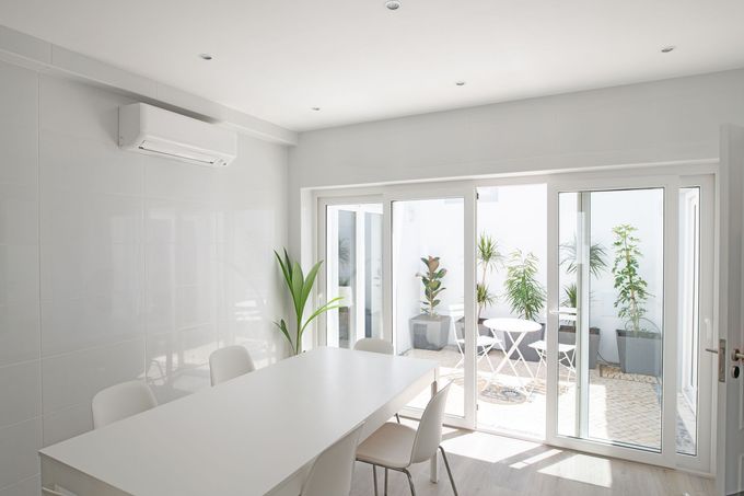 A white dining room with a table and chairs and sliding glass doors leading to a patio.