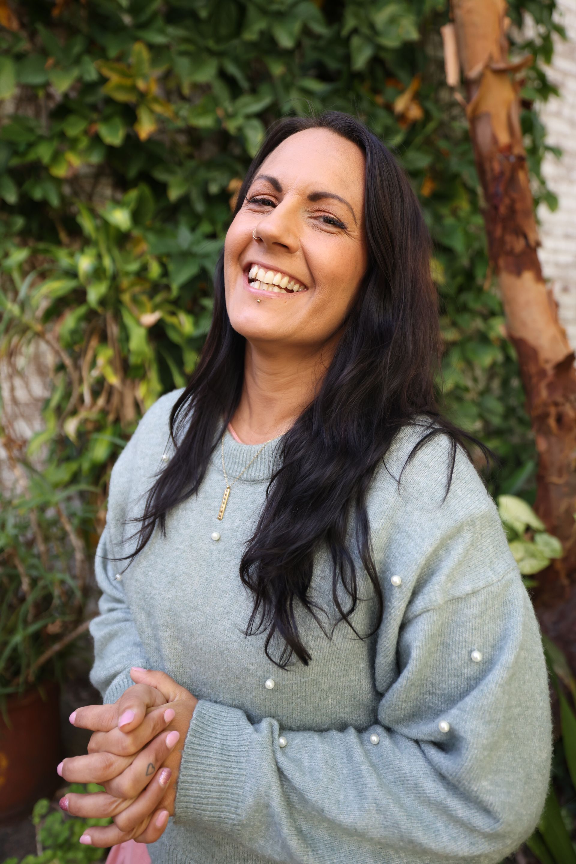 A Woman in a Blue Sweater is Smiling and Standing in Front of a Tree —Mind Breath Soul In Byron Bay, NSW