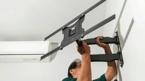 A man mounting a TV mount to a wall