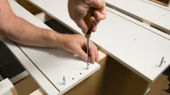 A person screwing together pieces of furniture