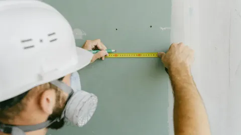A man measuring a piece of drywall