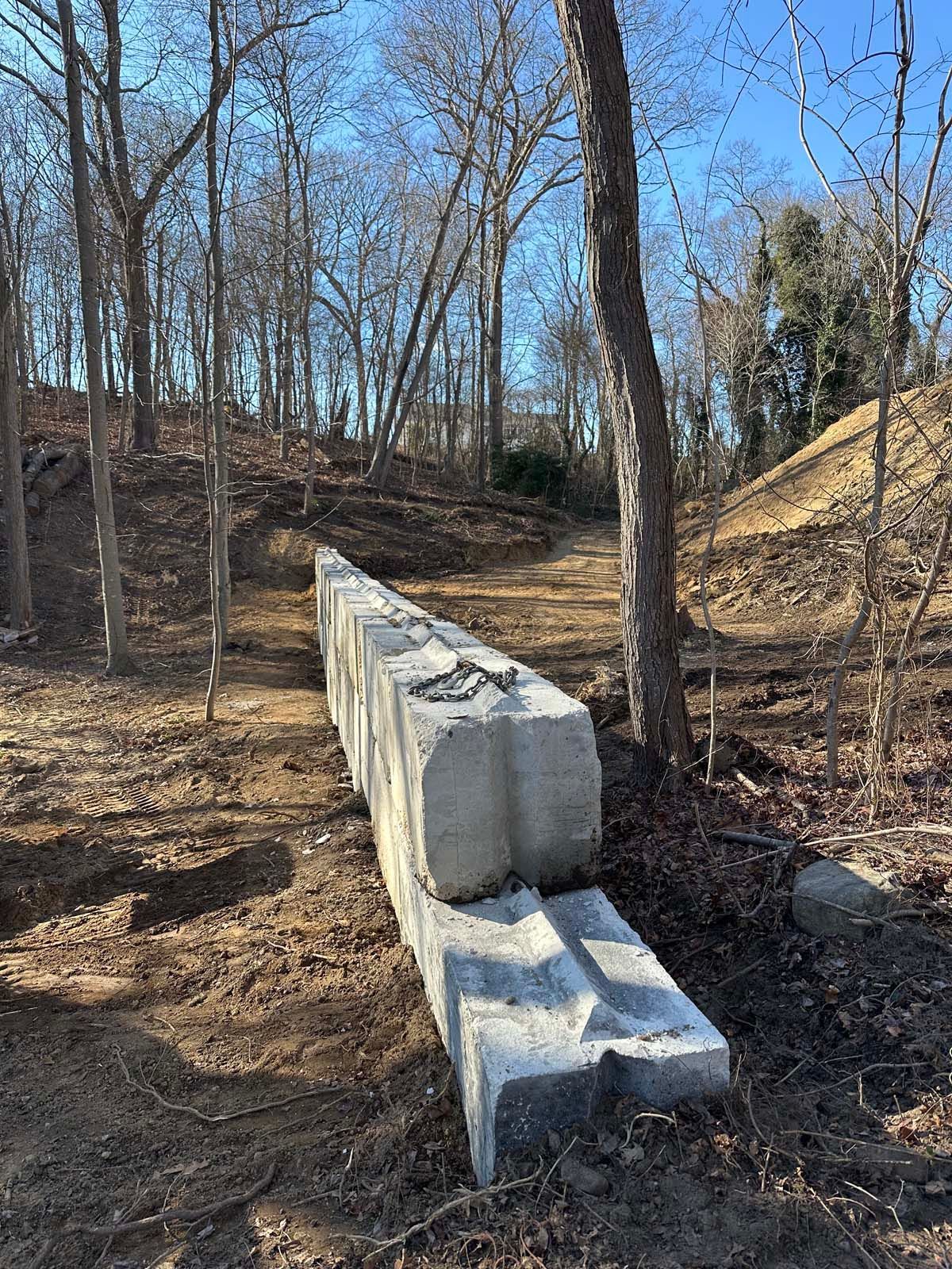 Concrete retaining wall blocks along a wooded trail.