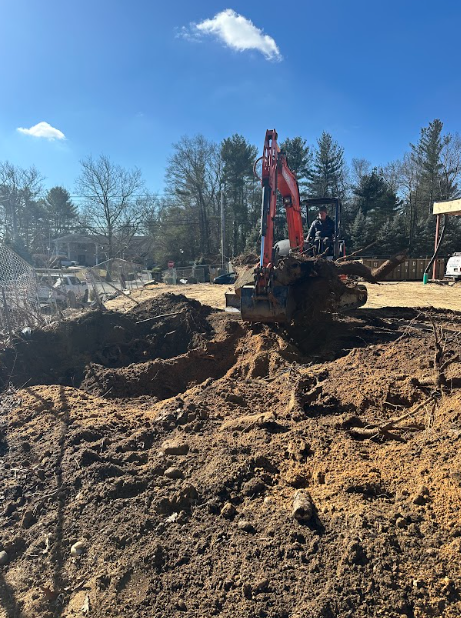 An excavator digs into the brown earth on a sunny day.