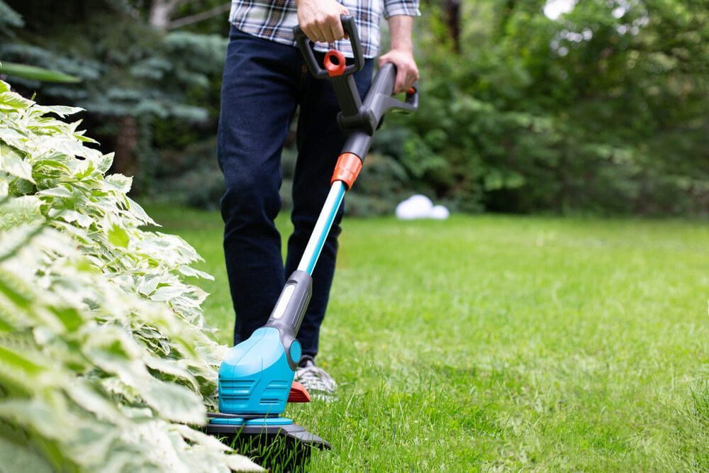 A Man is Using a Lawn Mower to Cut the Grass — Alice Springs Carpet Cleaning In Alice Springs, NT