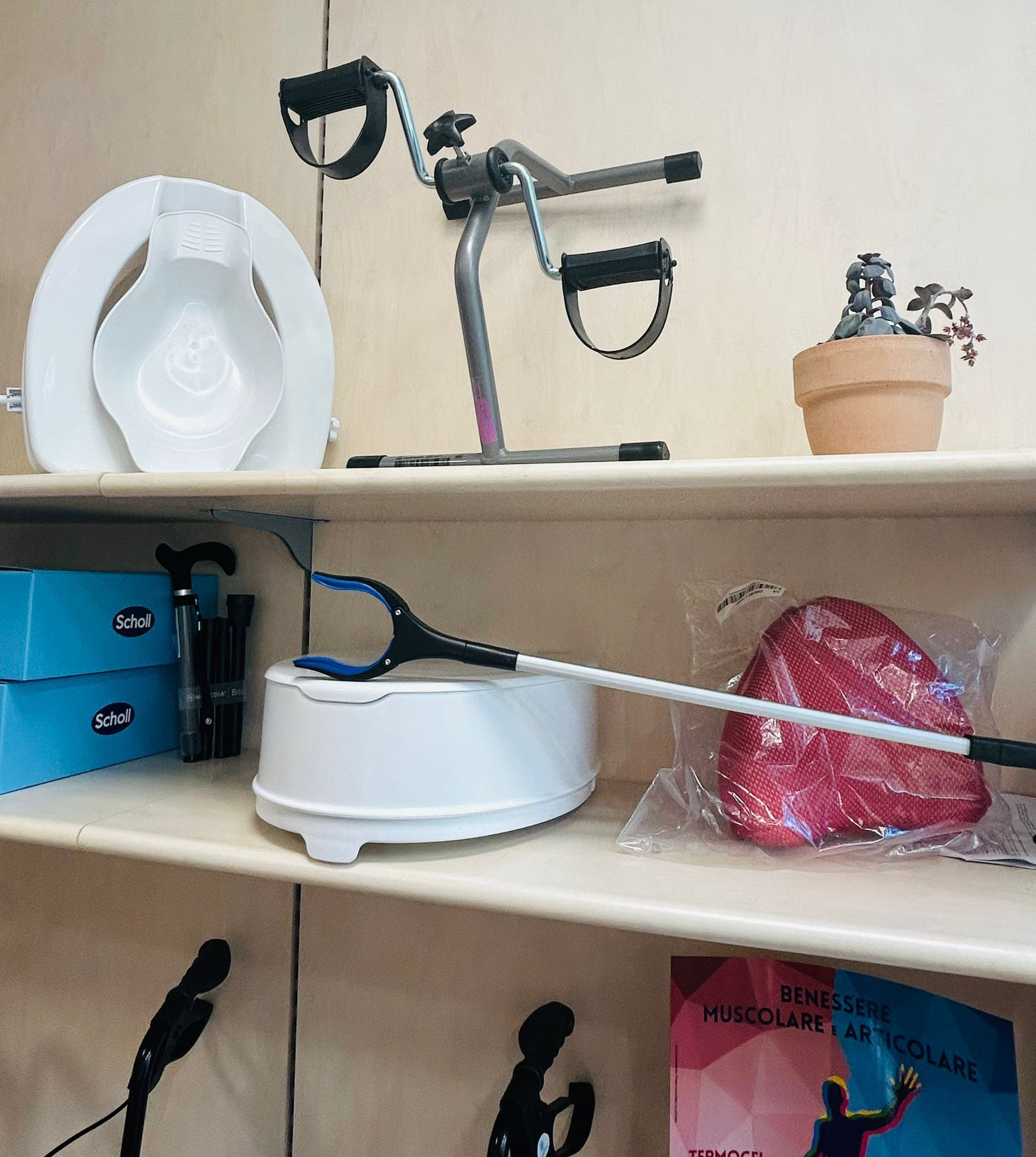 Scaffali che espongono ausili per l'accessibilità: sedile del water, attrezzatura per esercizi, strumento per raggiungere il corpo, comoda e padella per letto.