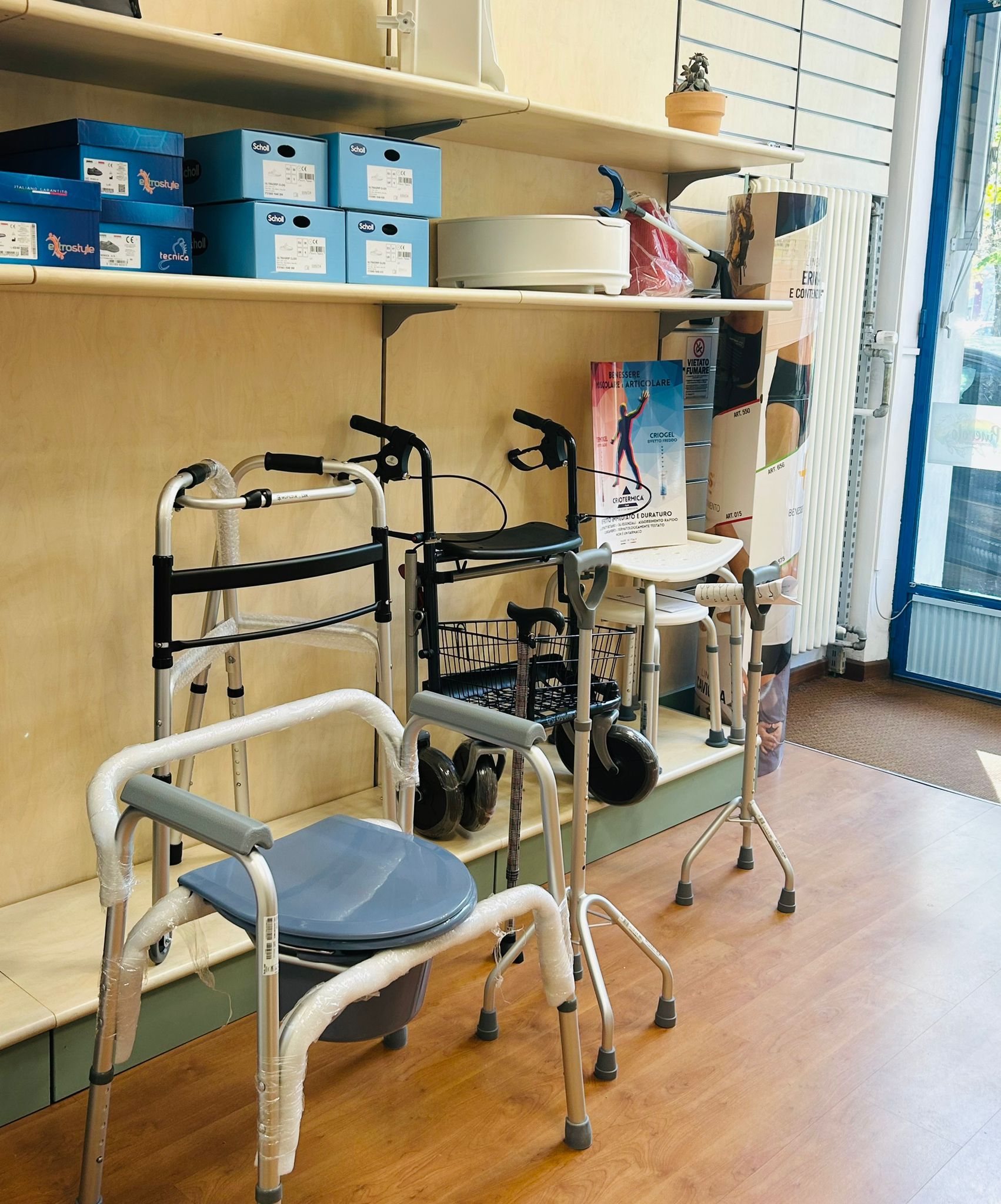 Esposizione di attrezzature mediche: deambulatori, sedia comoda, scaffali con forniture.
