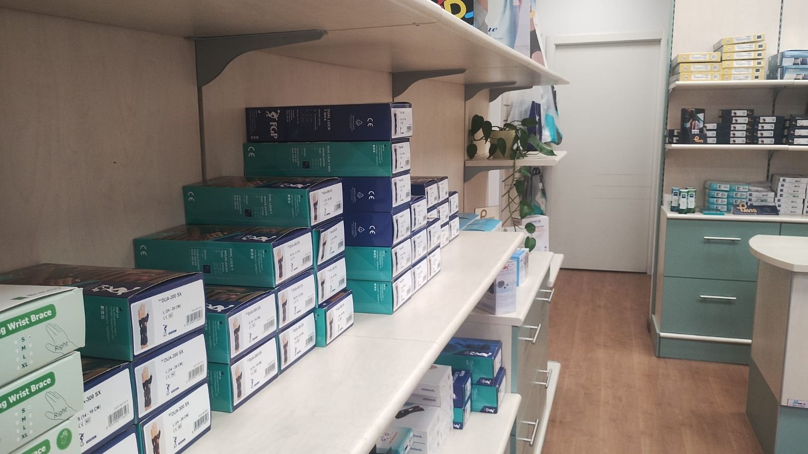 Scaffali pieni di scatole in un negozio; per lo più verdi e blu, disposte in pile. Scaffale, porta e un bancone.