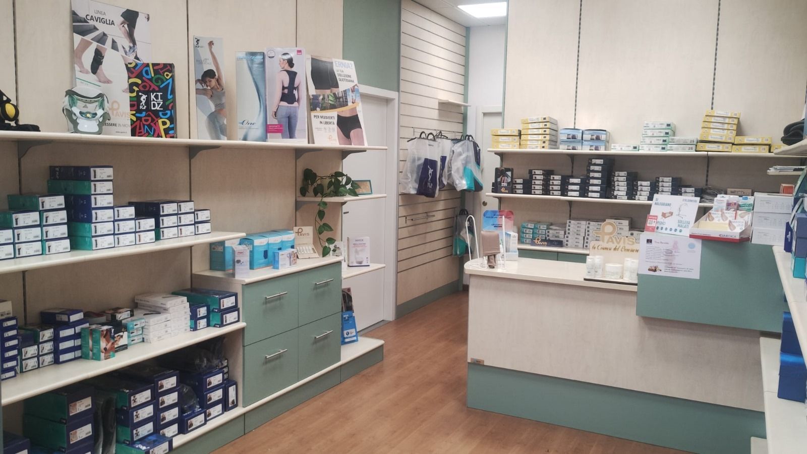 All'interno di un negozio: scaffali con prodotti confezionati, bancone sul retro, pareti chiare, pavimento in legno.
