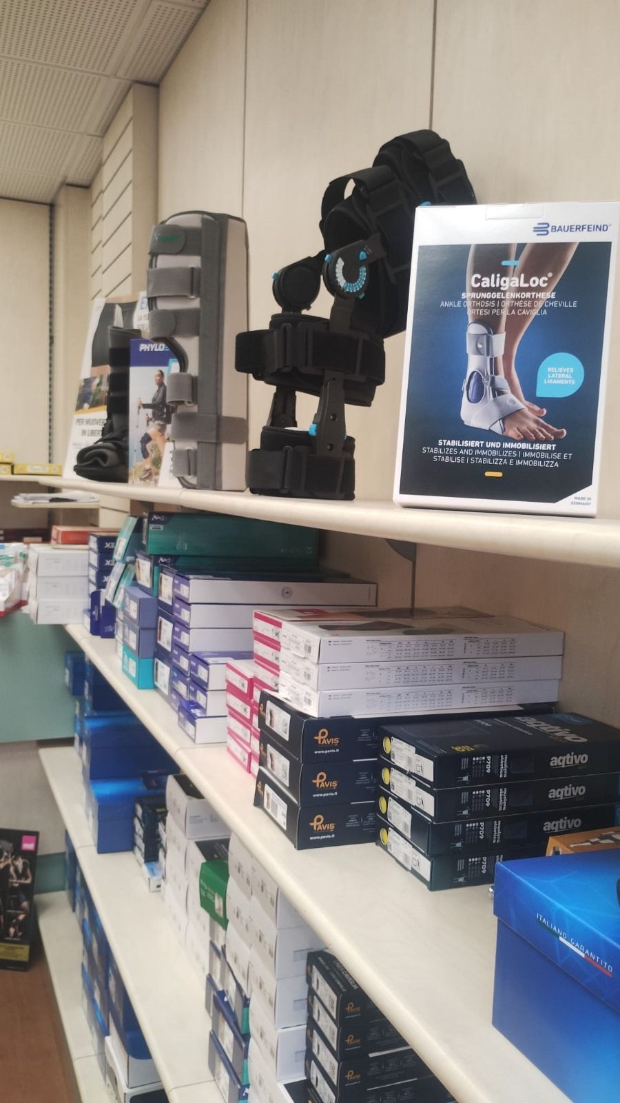 Scaffali pieni di forniture mediche ortopediche: tutori, supporti e scatole di prodotti.
