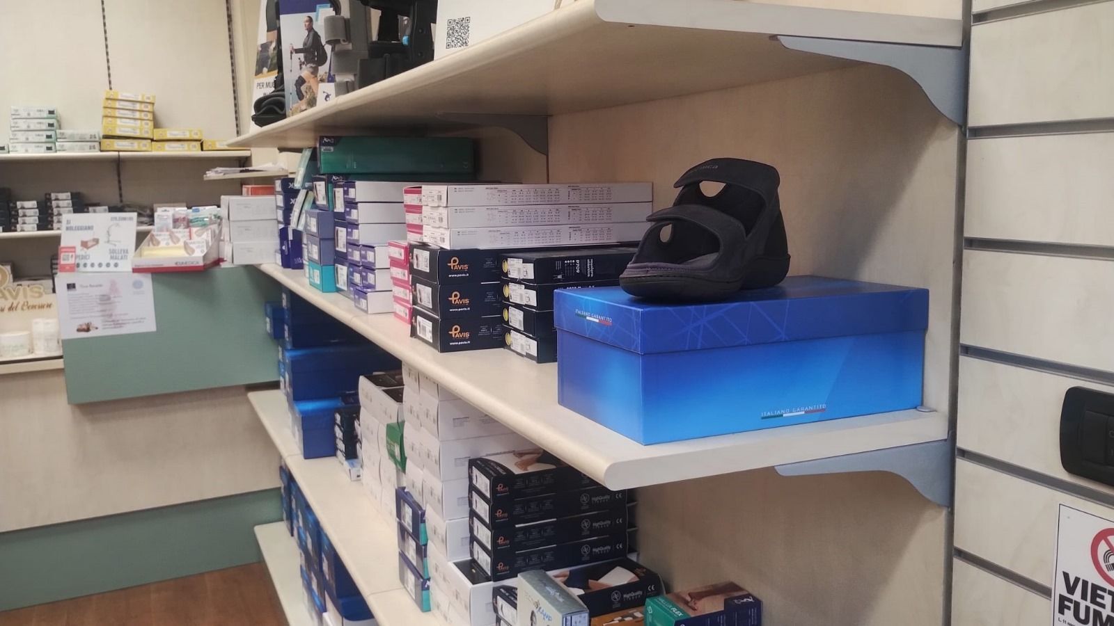 Gli scaffali di un negozio espongono scatole e uno stivale ortopedico nero.