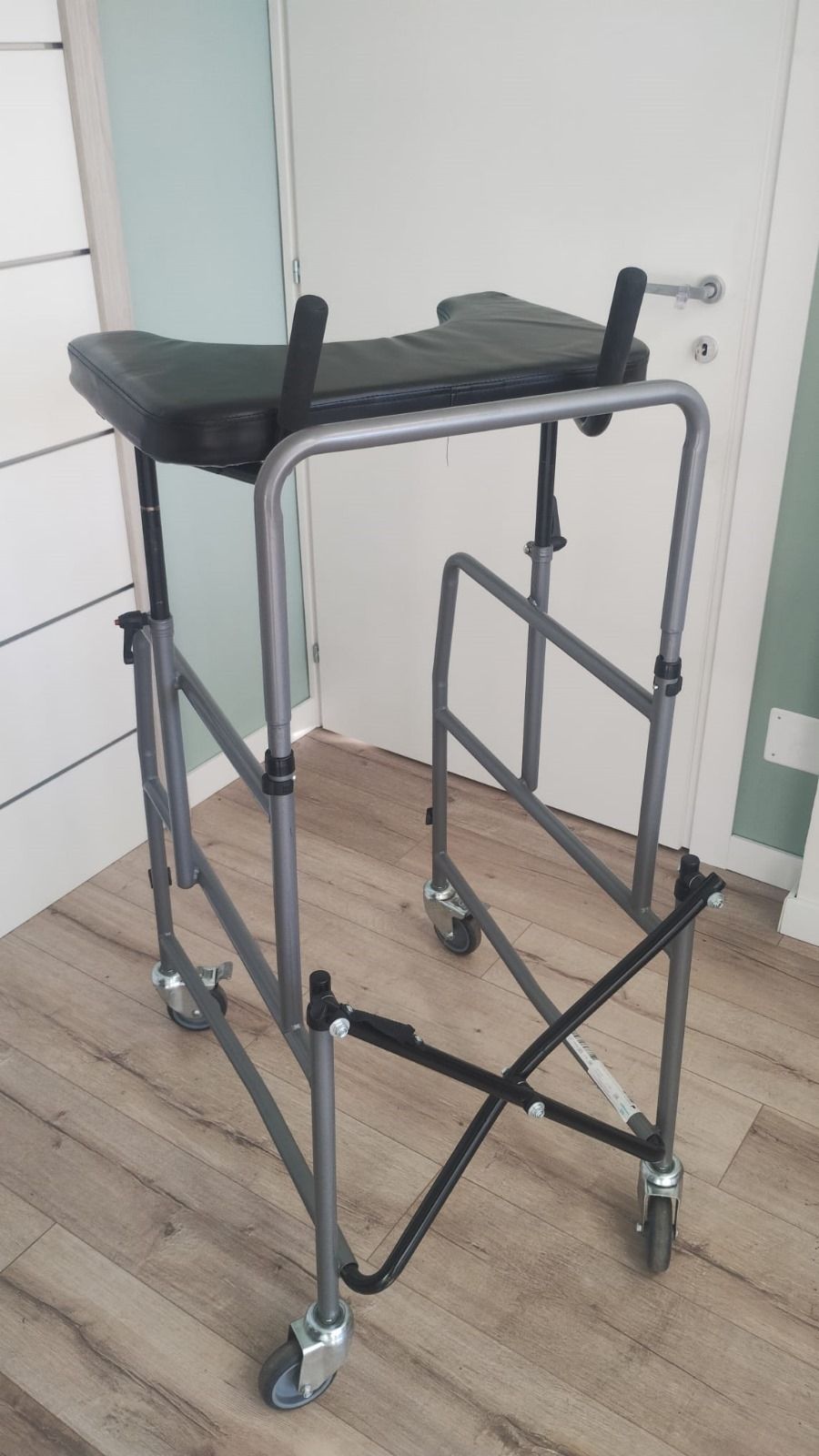 Deambulatore medico grigio con sedile e ruote, per interni.