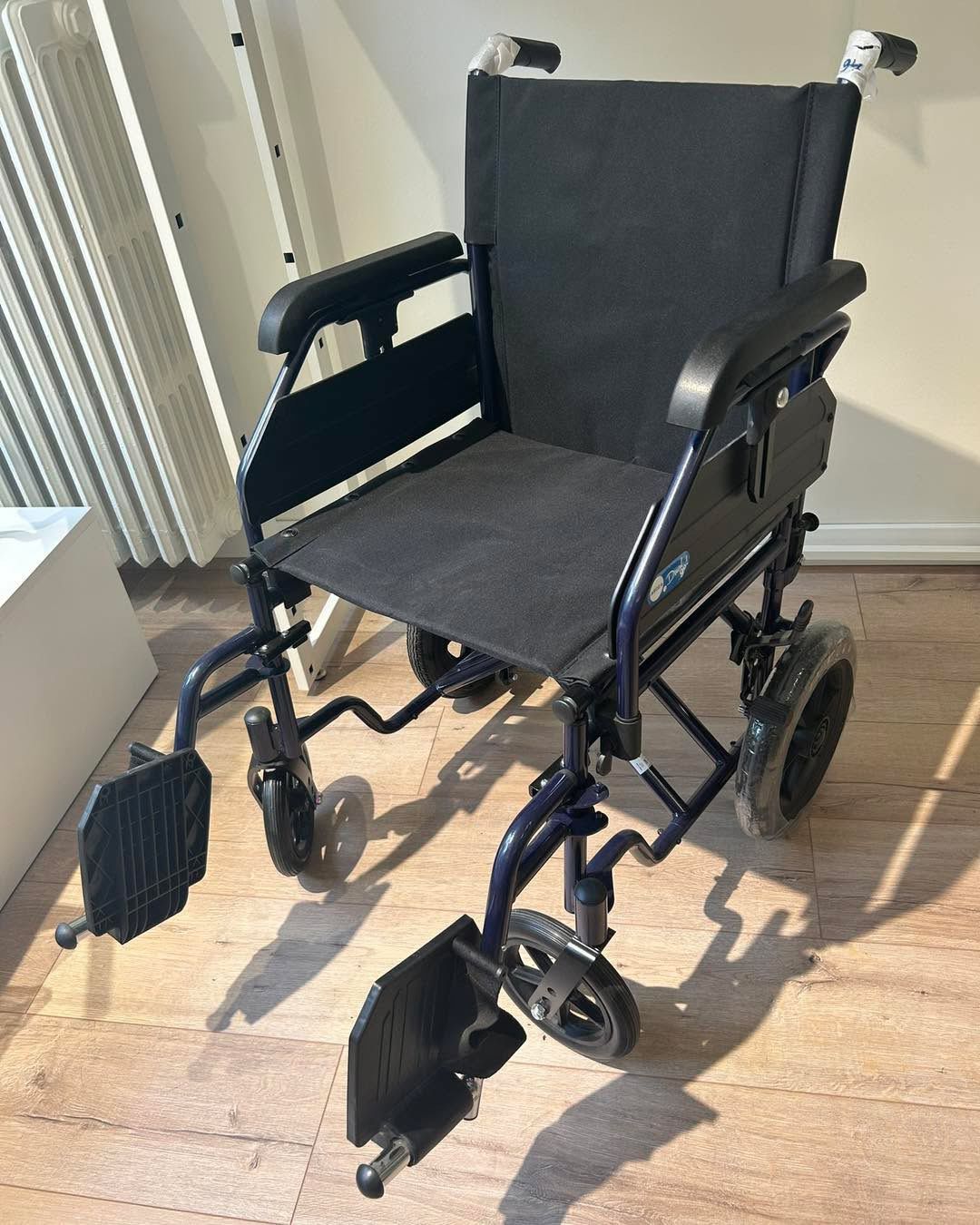 Sedia a rotelle blu su pavimento in legno, con poggiapiedi e braccioli.