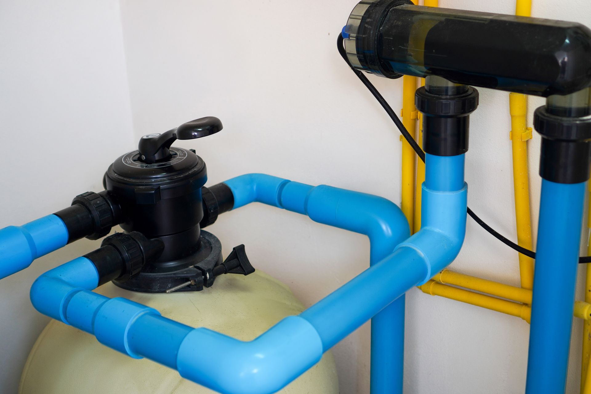 Pool filter system with blue pipes and black valves.
