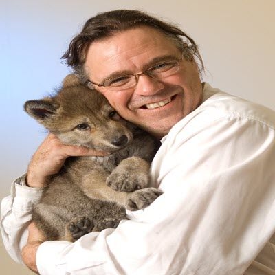 Matt Paproski hugging a wolf puppy.
