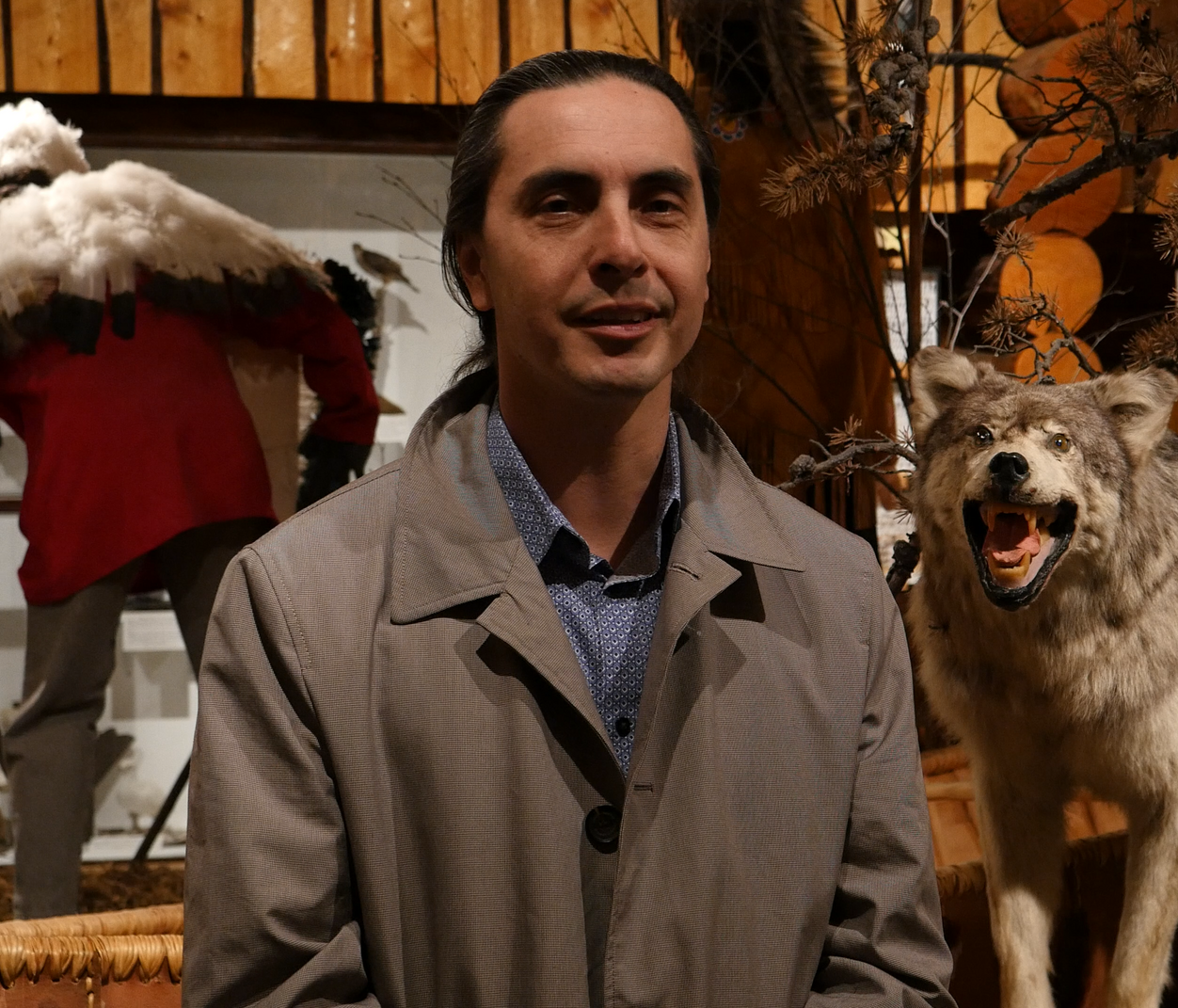 Former Manitoba grand chief Arlen Dumas standing in front of stuffed wolves in a visitor centre.