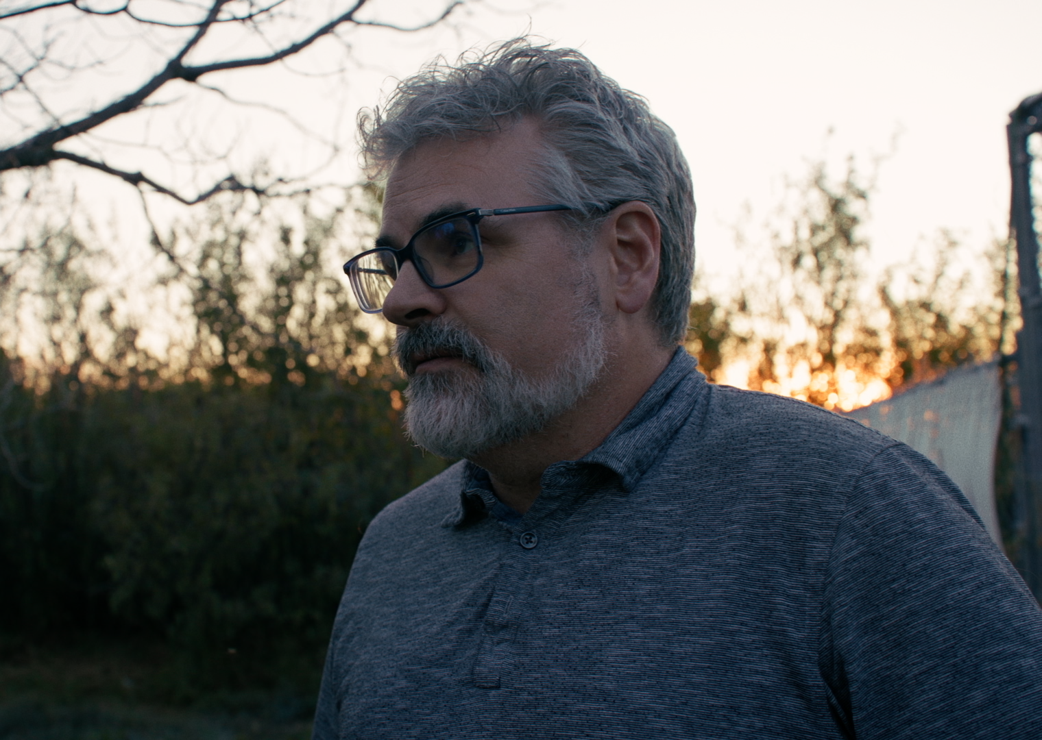 Veterinarian Dwayne Groves standing in wolf enclosure at sunset.