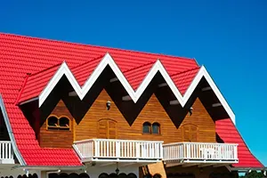 House with bright red zigzag roof and white trim against a blue sky.