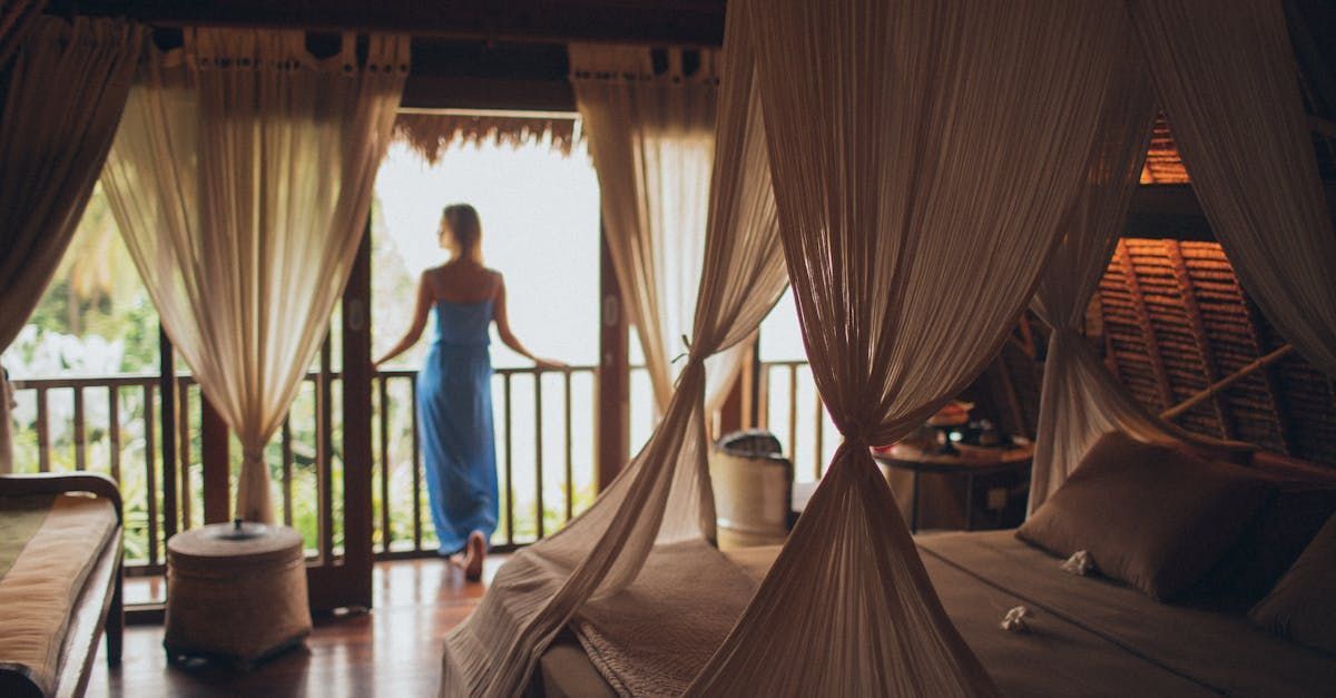 A woman is standing on a balcony in a hotel room looking out the window.