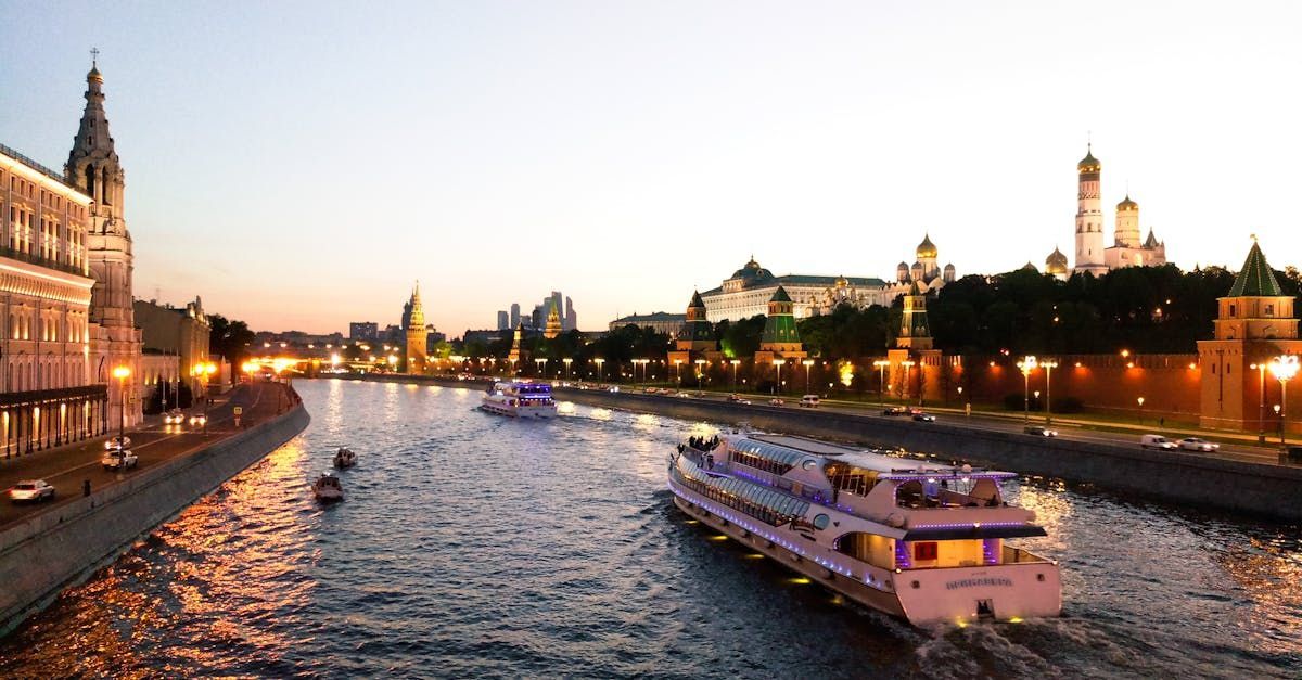 A boat is floating on a river in a city at night.