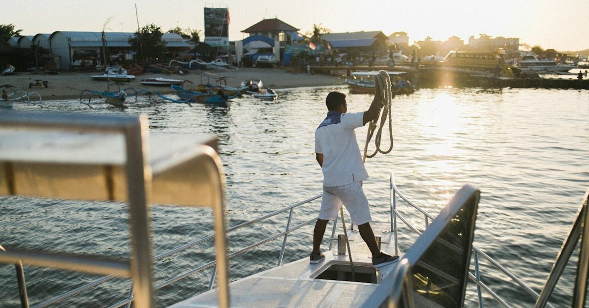 A man is standing on a boat in the water holding a rope.