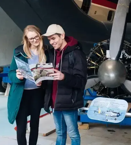 A man and a woman are looking at a map in front of an airplane.