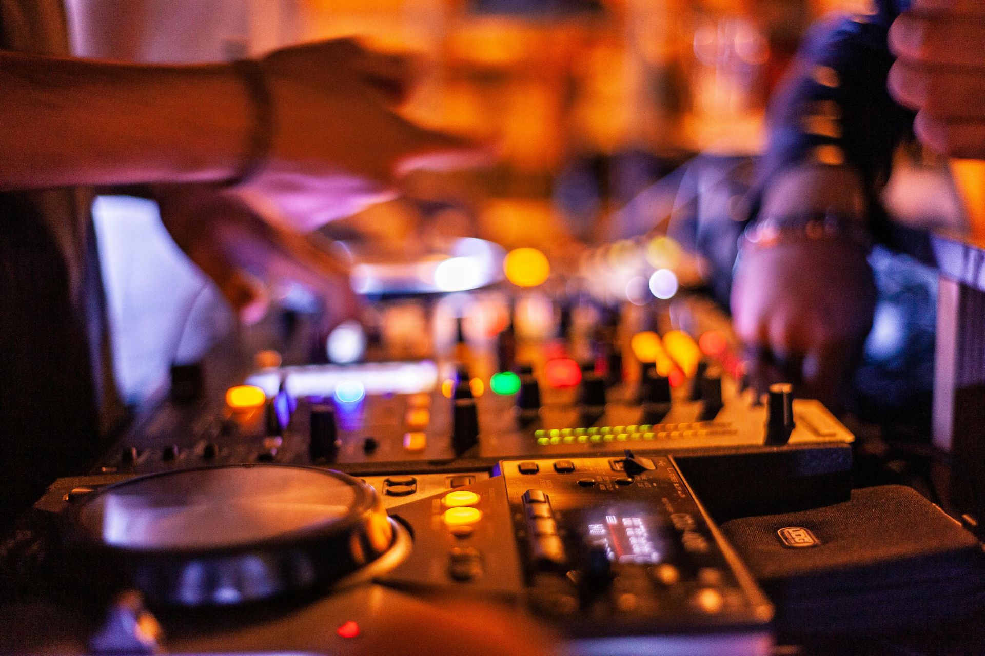 A dj is playing music on a mixer at a party.