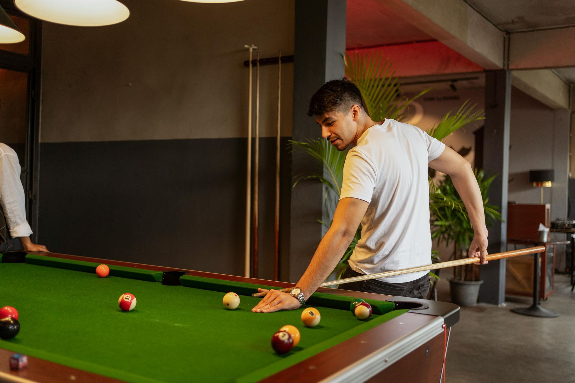 A man is playing pool in a pool hall.