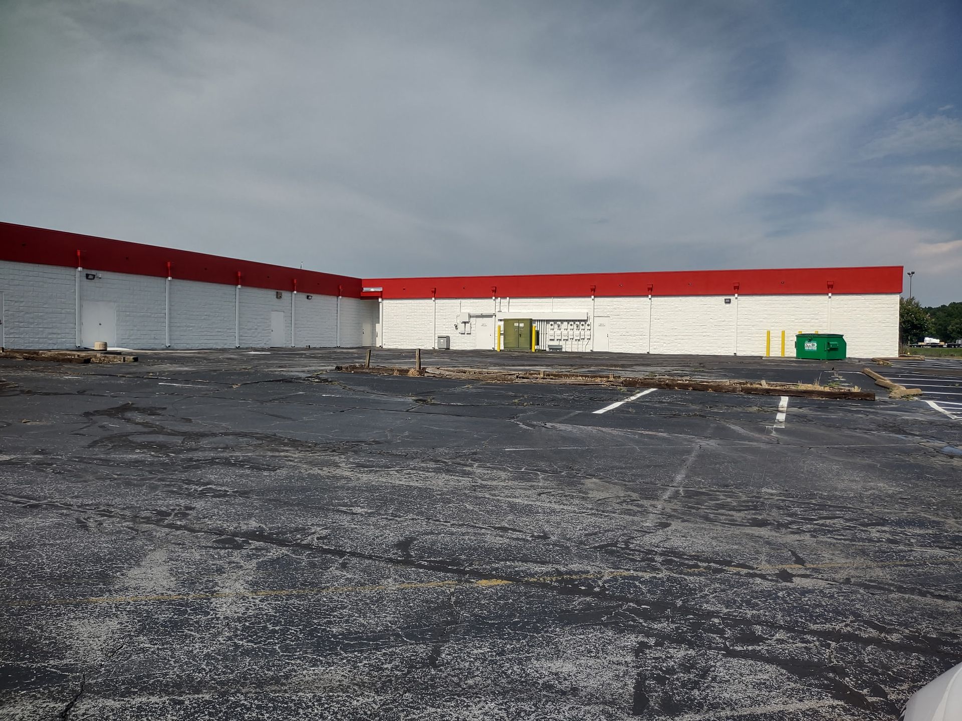 An empty parking lot in front of a large white building with a red roof