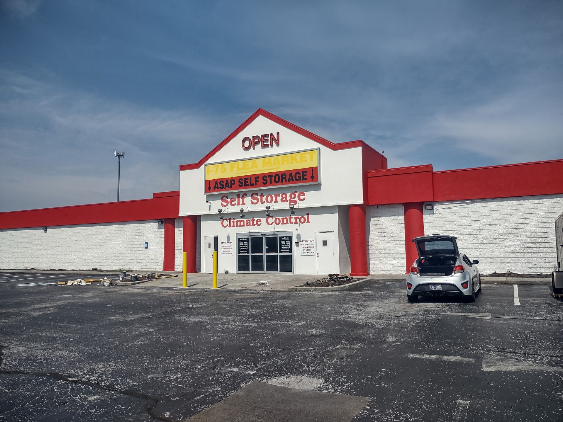 A white car is parked in front of a self storage building.