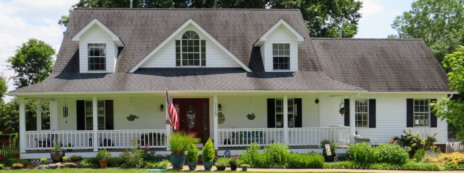 A large white house with a gray roof and black shutters