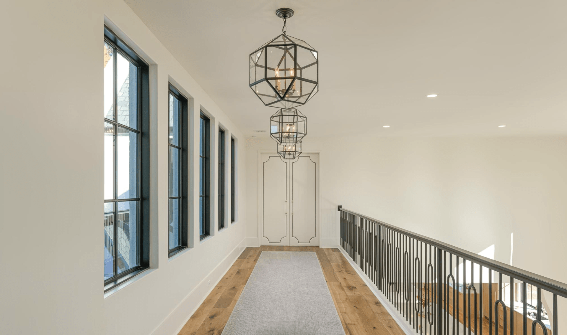 A long hallway with a railing and a lot of windows.