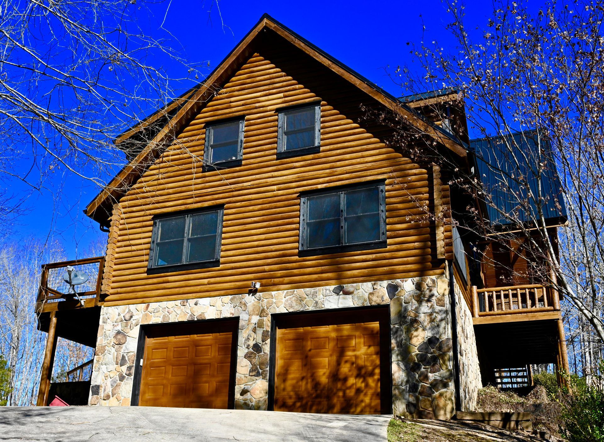 A large log cabin with two garage doors and a balcony