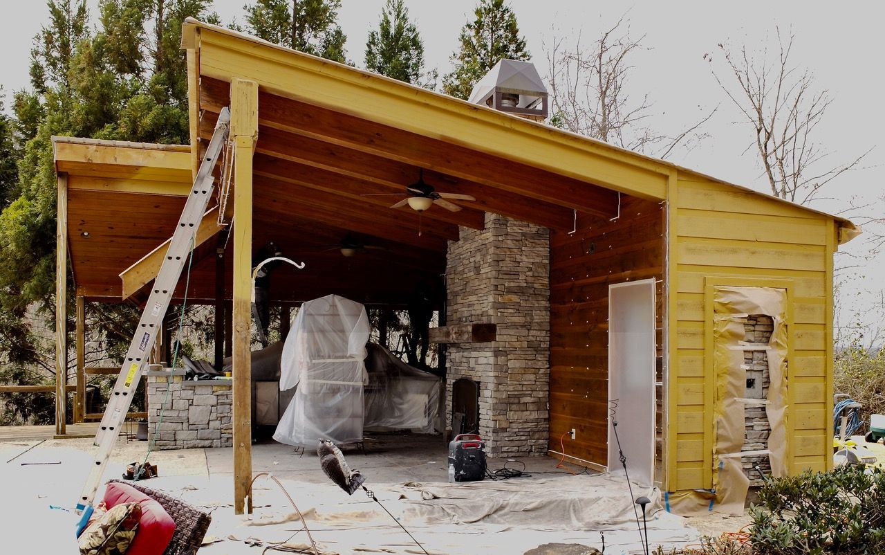 A house with a roof that is covered in wood and a stone fireplace.