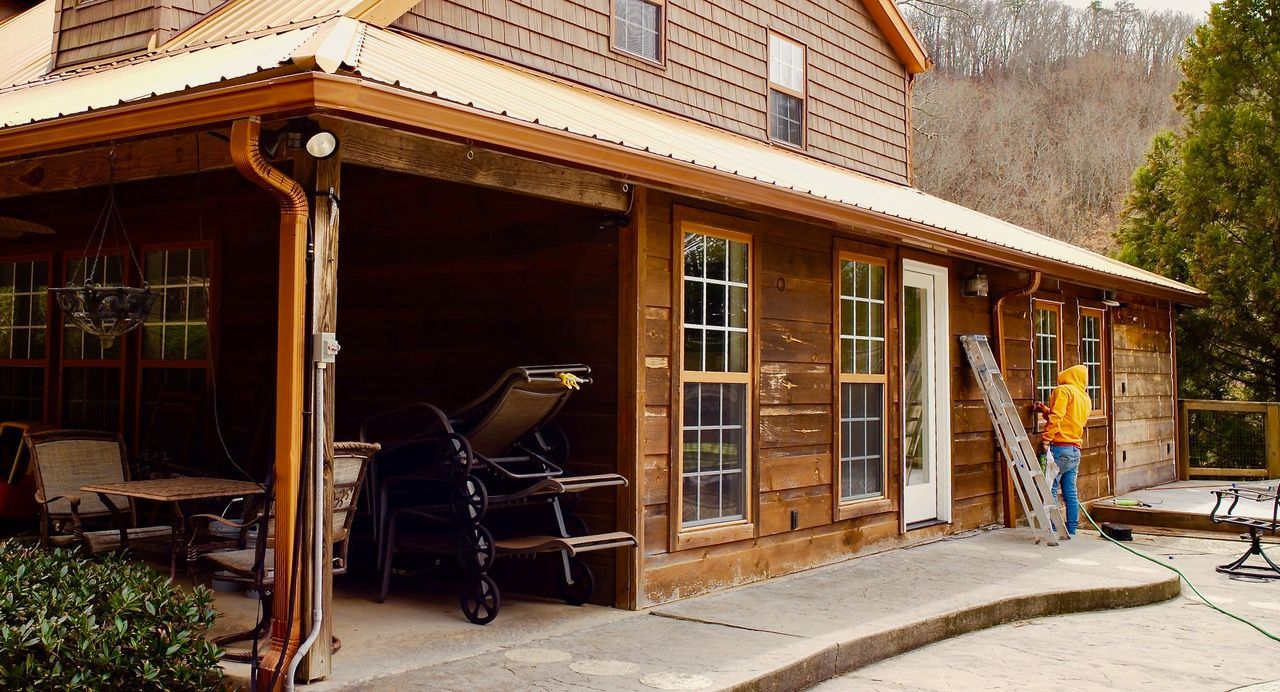 A man is standing on the porch of a wooden house.