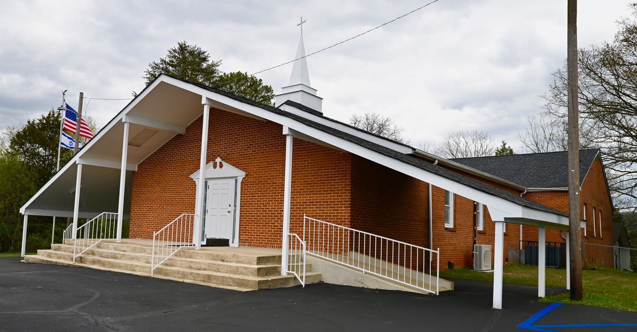 A brick church with a white steeple and stairs